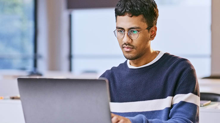 A college age student working at his laptop.
