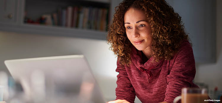 A women wearing a purple sweather working on a laptop
