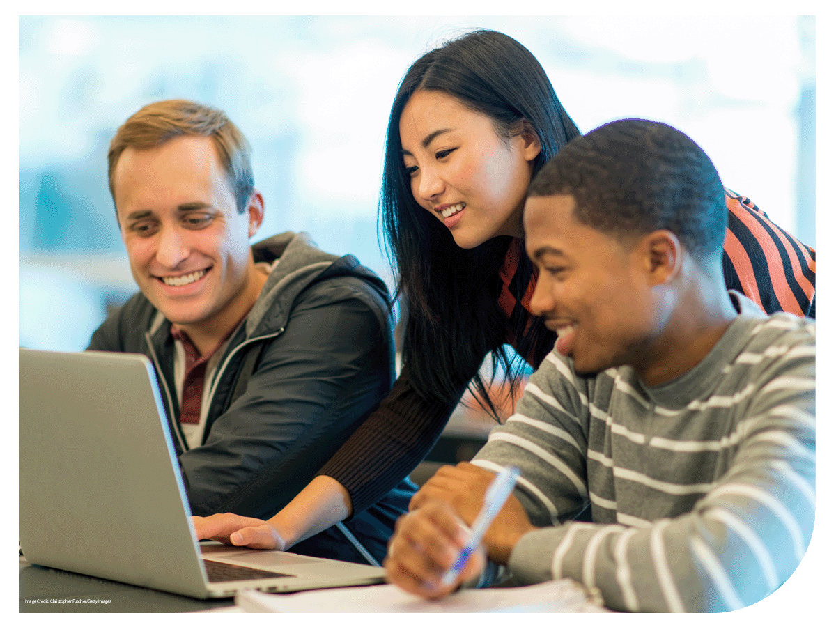 students smiling gathered around a laptop