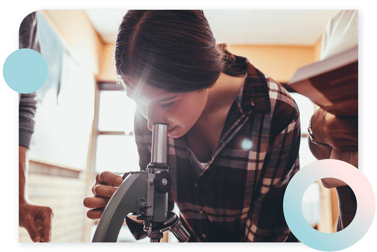 A photograph shows a girl looking through the eyepiece of a microscope.